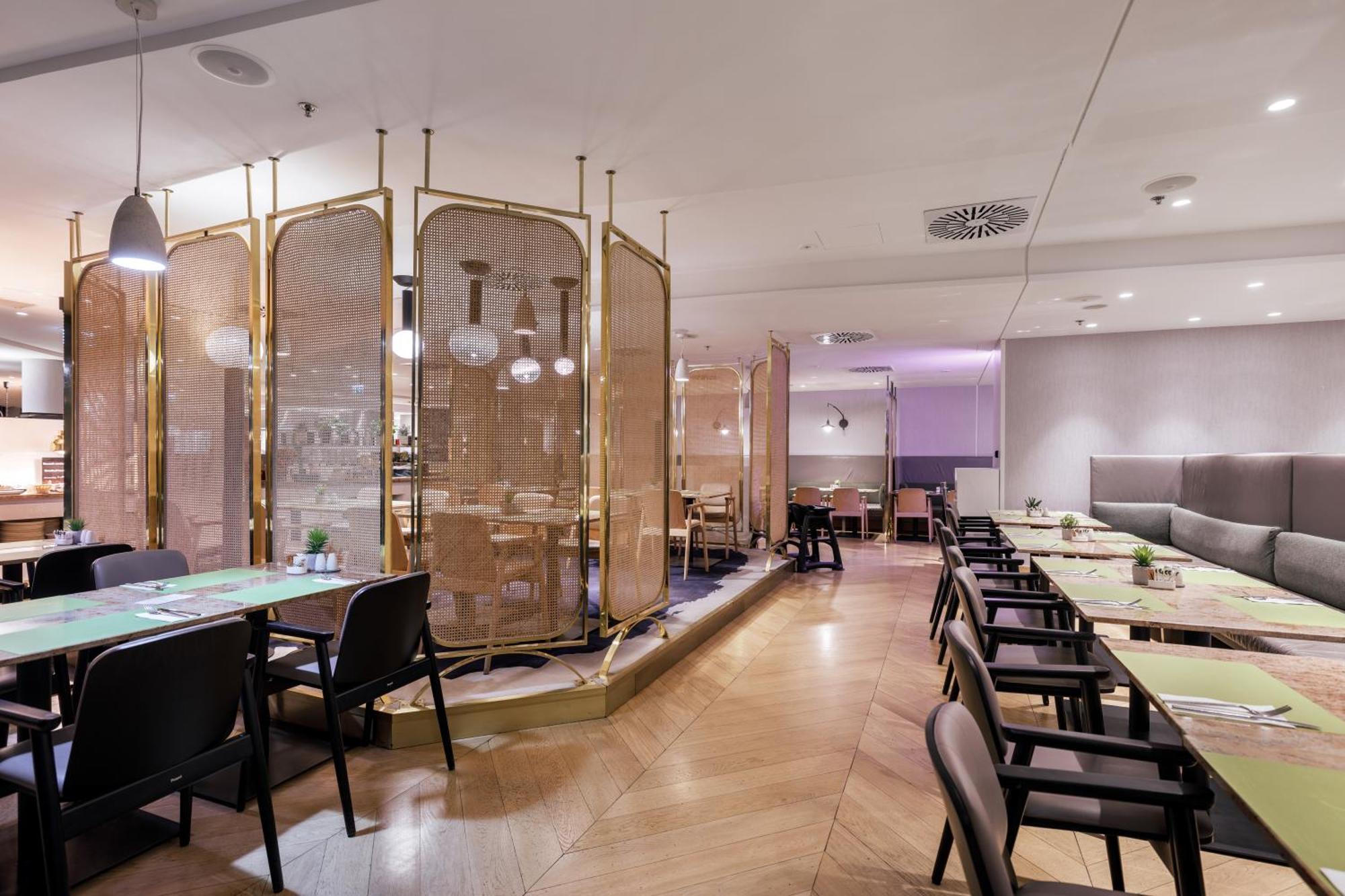 Radisson Blu Resort 슈비노우이스쳬 외부 사진 The photo depicts a modern restaurant interior. It features a layout with several tables and chairs arranged in an organized manner. There is a decorative partition made of delicate mesh or fabric, providing some privacy between different dining area