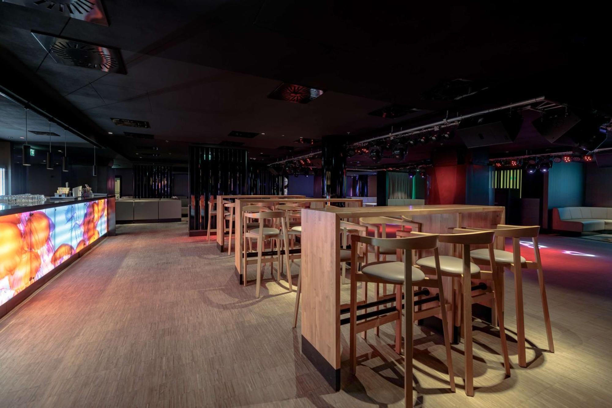 Radisson Blu Resort 슈비노우이스쳬 외부 사진 The photo shows an interior space that appears to be a bar or lounge. It features a modern design with a dark color scheme. There are several wooden high-top tables with matching stools arranged in the area. In the background, there is a bar counter,