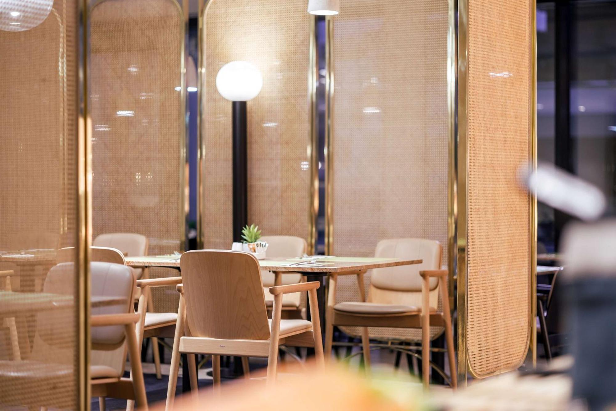 Radisson Blu Resort 슈비노우이스쳬 외부 사진 The image shows an interior space, likely part of a restaurant or café. There are several wooden chairs arranged around tables, and the overall decor features soft lighting and warm colors. The walls appear to be partially covered with a woven materi