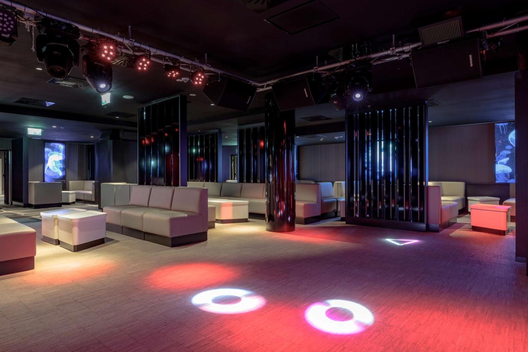 Radisson Blu Resort 슈비노우이스쳬 외부 사진 The photo depicts a modern nightclub interior, featuring a spacious layout with sleek, minimalist seating arrangements. The room has plush seating along the walls, and the floor is illuminated with circular lights in varying colors, creating a vibran