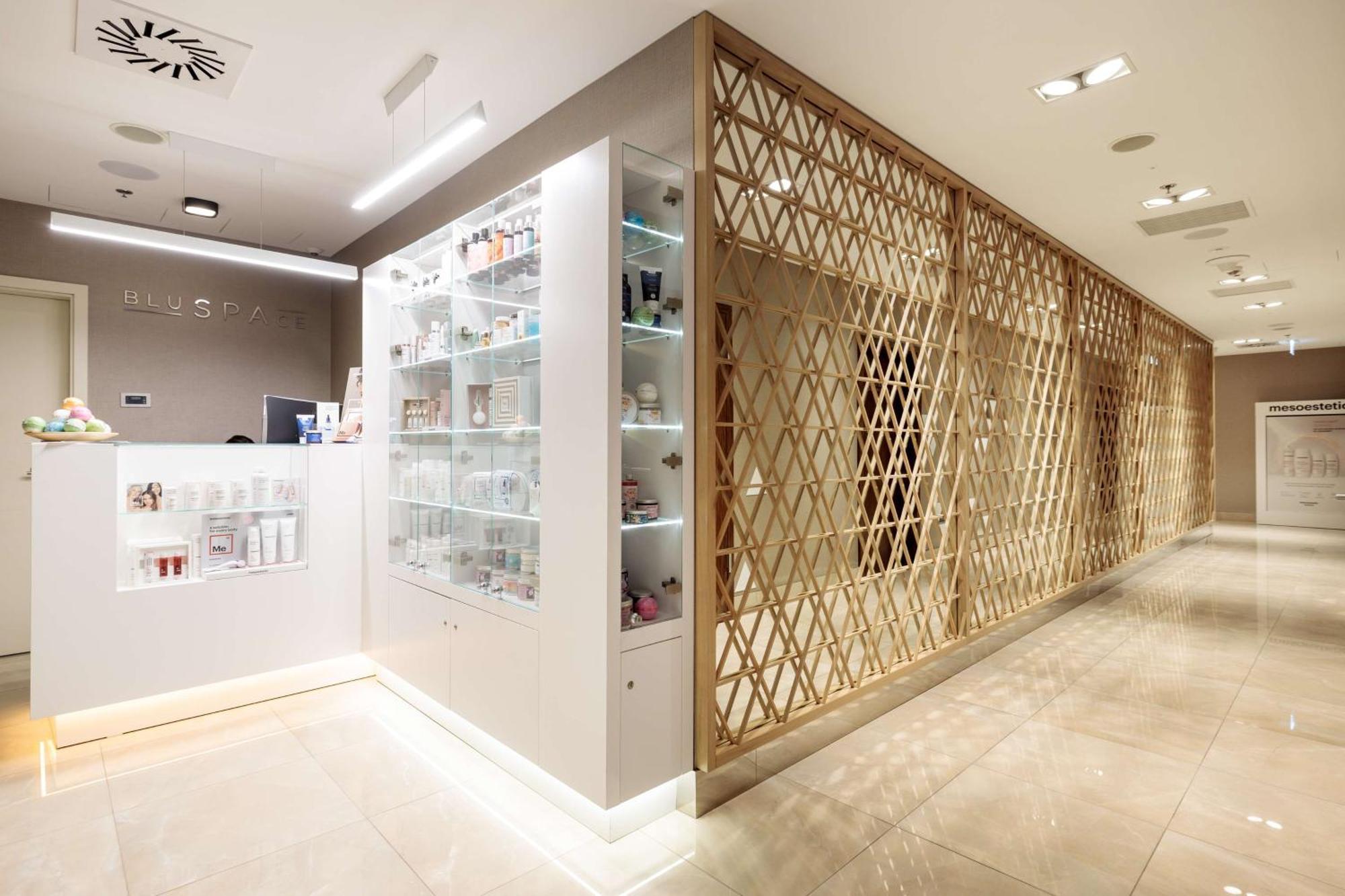 Radisson Blu Resort 슈비노우이스쳬 외부 사진 The photo shows a modern interior, likely from a spa or skincare clinic. On the left, there is a reception area with a sleek white counter and an illuminated display showcasing various skincare products. The wall behind the reception features a glass