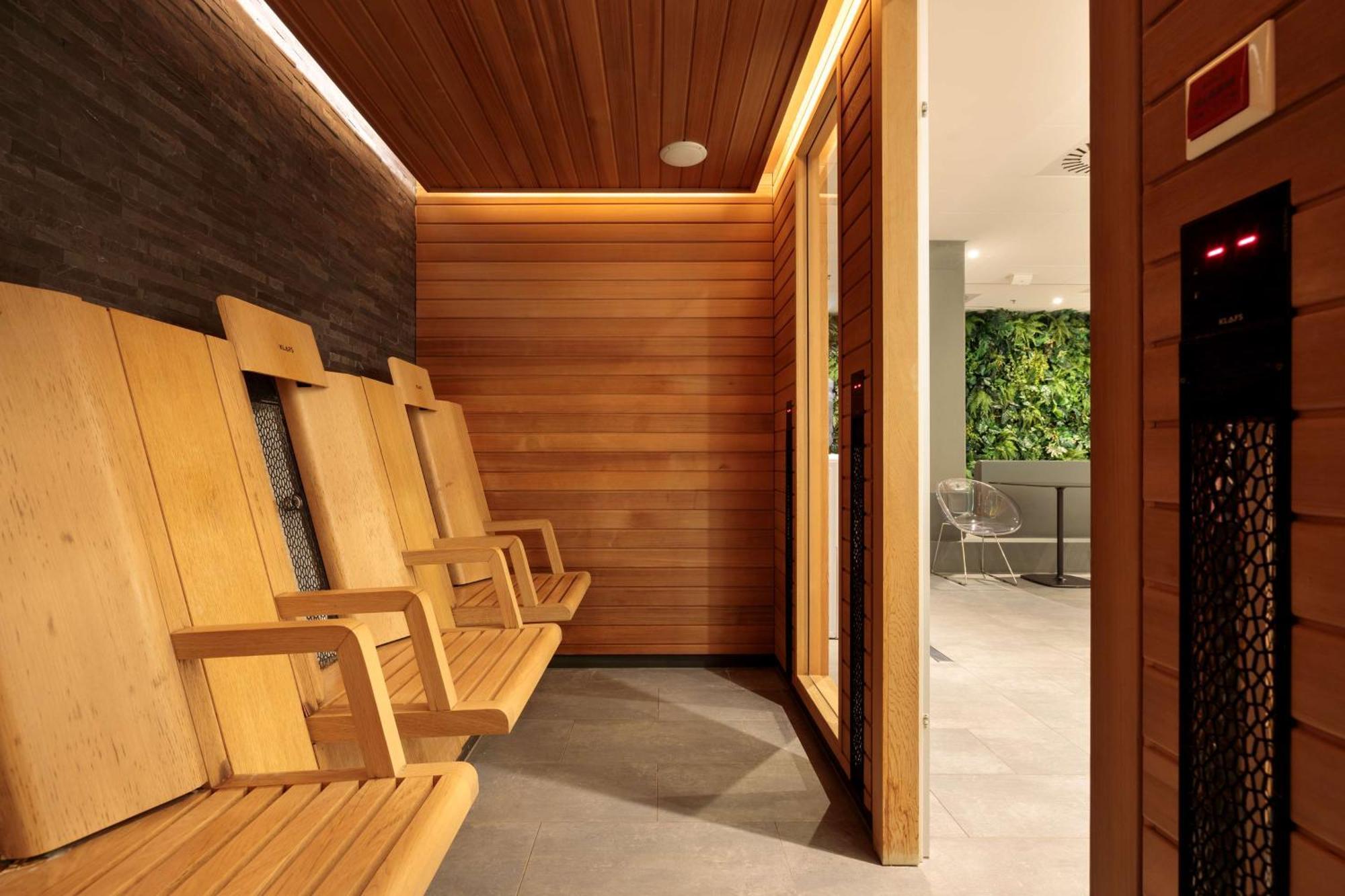 Radisson Blu Resort 슈비노우이스쳬 외부 사진 The photo shows a sauna area featuring wooden benches arranged along the walls. The interior is designed with natural wood paneling and has a warm, inviting ambiance. There is a glass door visible, which likely leads to another space, and some greene