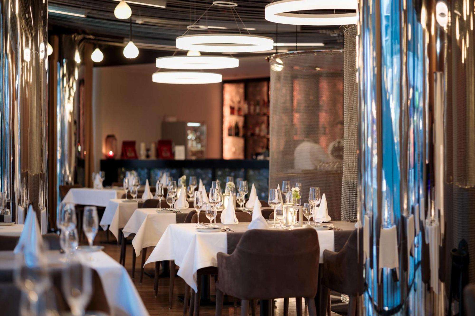 Radisson Blu Resort 슈비노우이스쳬 외부 사진 The photo depicts an elegant restaurant interior. There are several tables covered with white tablecloths, each set with glassware and napkins, suggesting a fine dining experience. The chairs are upholstered, providing a comfortable seating arrangeme